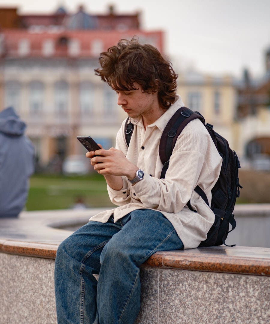 A teenager with a school backpack sitting outside, checking in on his phone